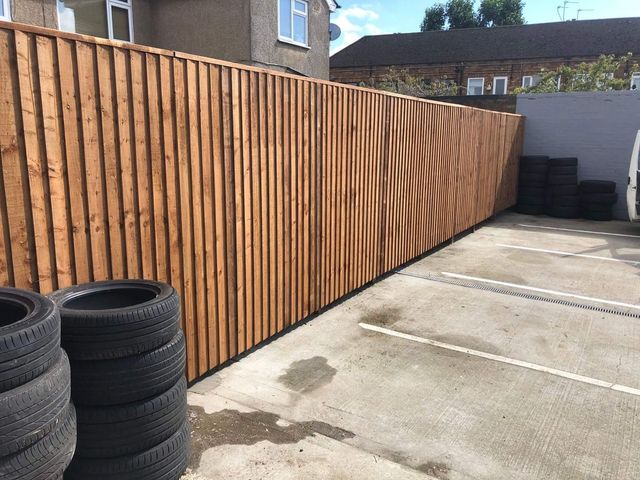 A long run of closeboard fencing along a concrete yard