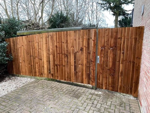 Closeboard fencing running along a block-paved driveway